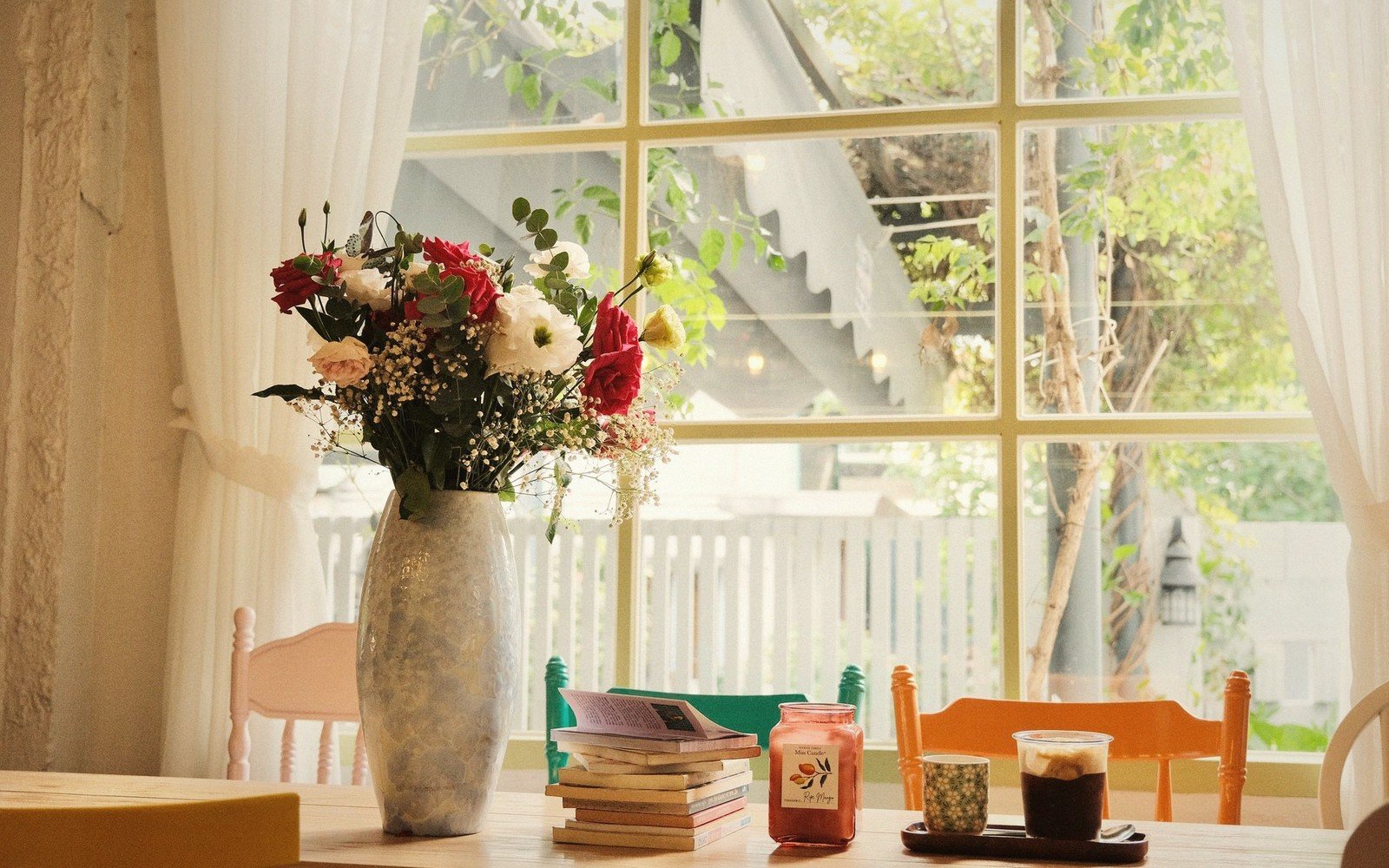 A reading chair beside a window with a book on its arm