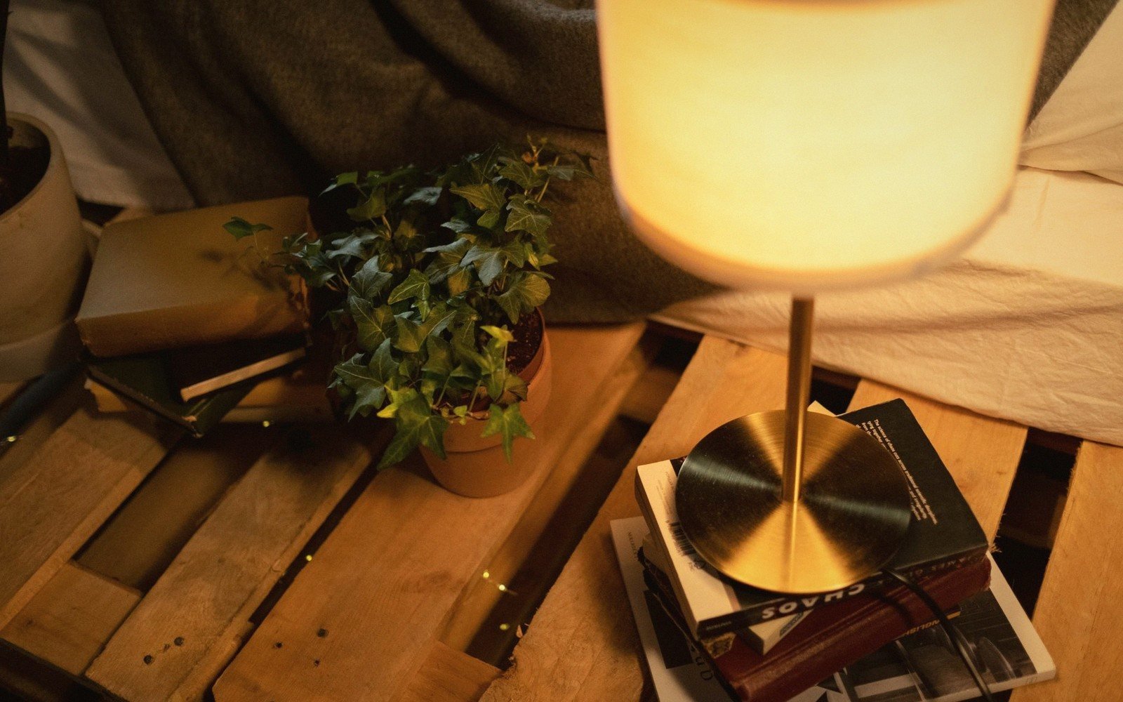 Stack of hardback books on a table in warm lamplight